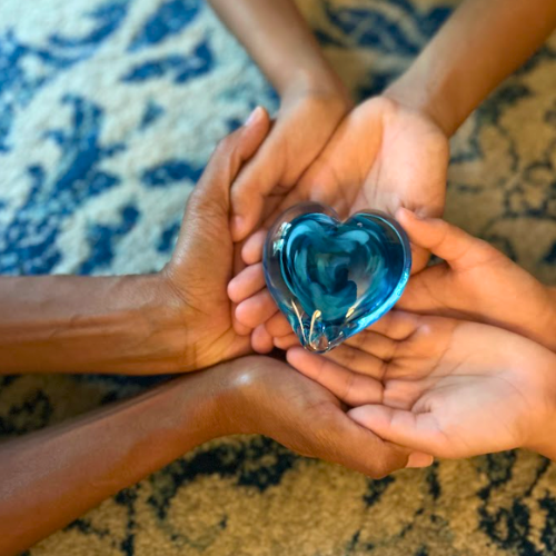 Hands cradling a blue glass heart — the Healing Journeys emblem